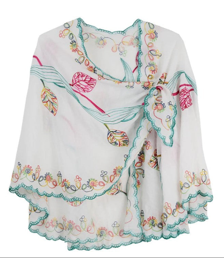 White cape with colorful floral embroidery on a white background