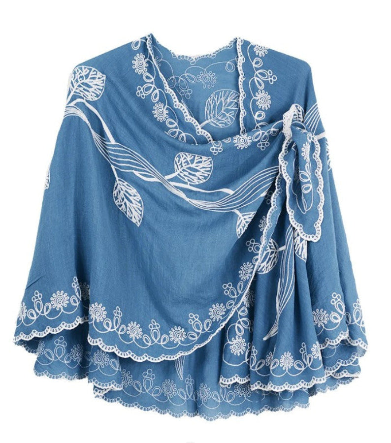 Blue cape with white floral embroidery on a white background