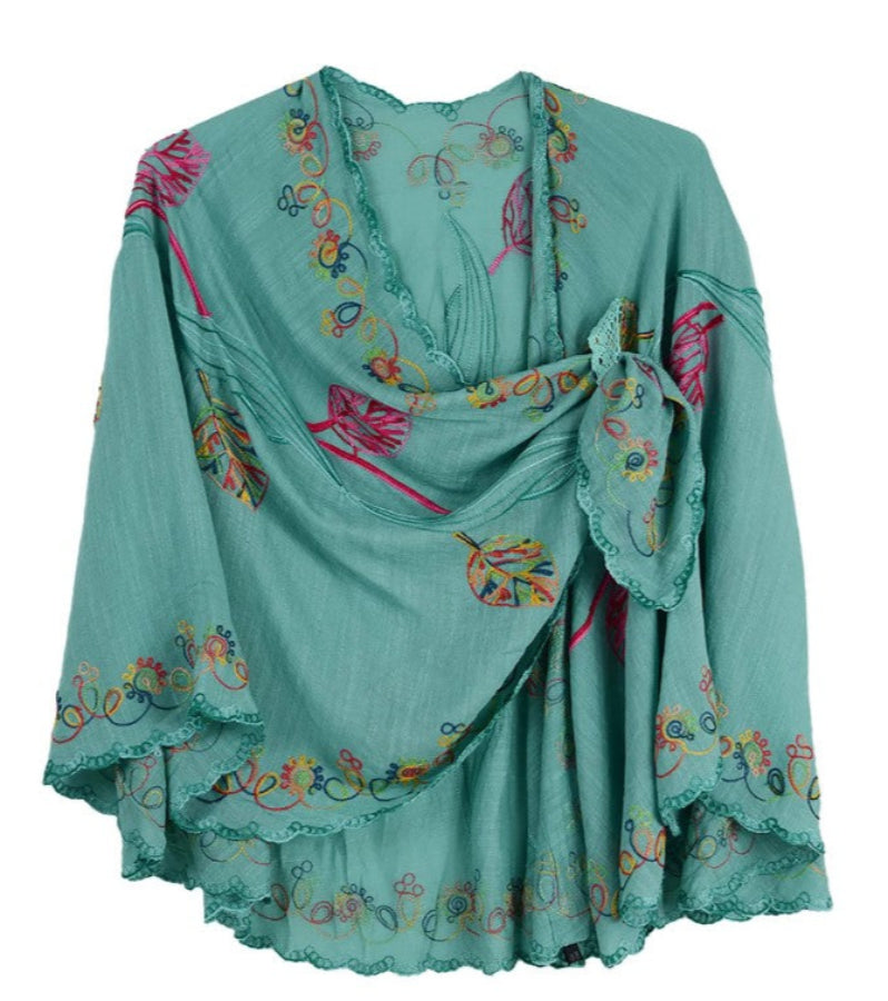 Turquoise cape with colorful floral embroidery on a white background